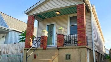 A two-story house with a front porch, a brick chimney, and a green awning.