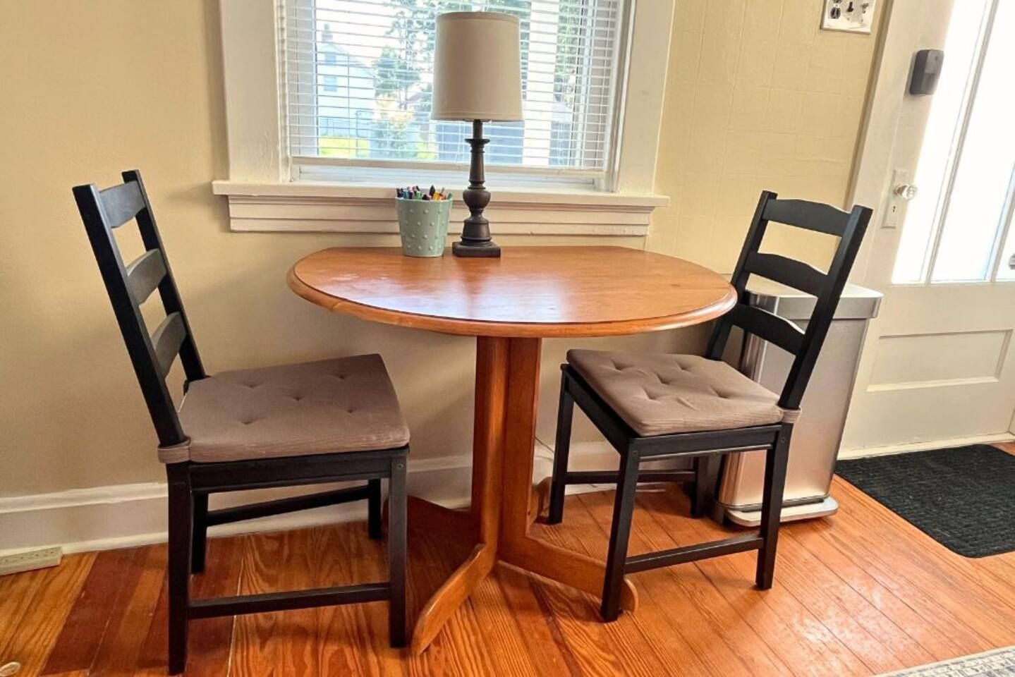 A small dining area with a round wooden table and two upholstered chairs.