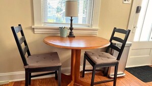 A small dining area with a round wooden table and two upholstered chairs. - The Hill District House - Kid Friendly, Walkable - Stay Smiley Rentals (St. Louis)