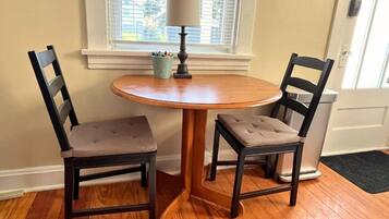 A small dining area with a round wooden table and two upholstered chairs.