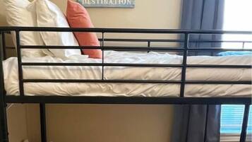 A bunk bed with two levels, each with pillows and a mattress. A poster is on the wall above the bed.