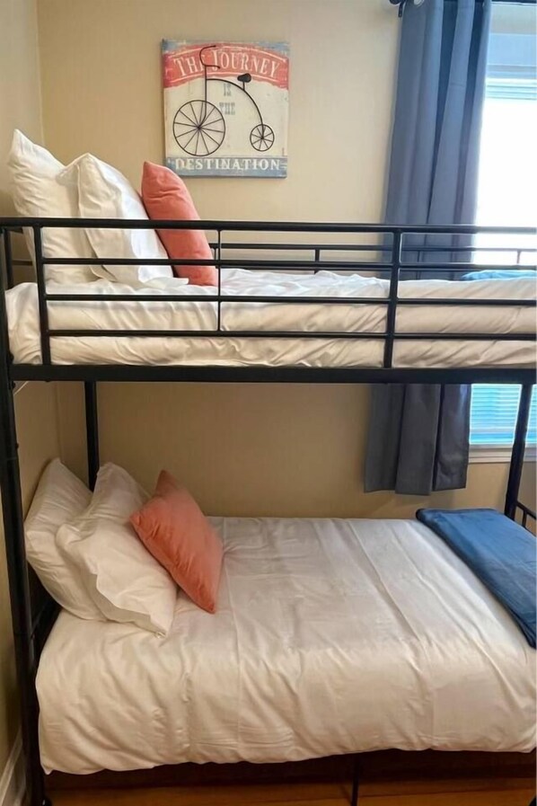 A bunk bed with two levels, each with pillows and a mattress. A poster is on the wall above the bed.