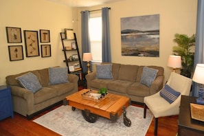 A living room with two sofas, a coffee table, a bookshelf, a painting, and a plant.