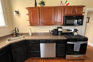 A kitchen with wooden cabinets, a stainless steel dishwasher, a black stove, and a microwave.
