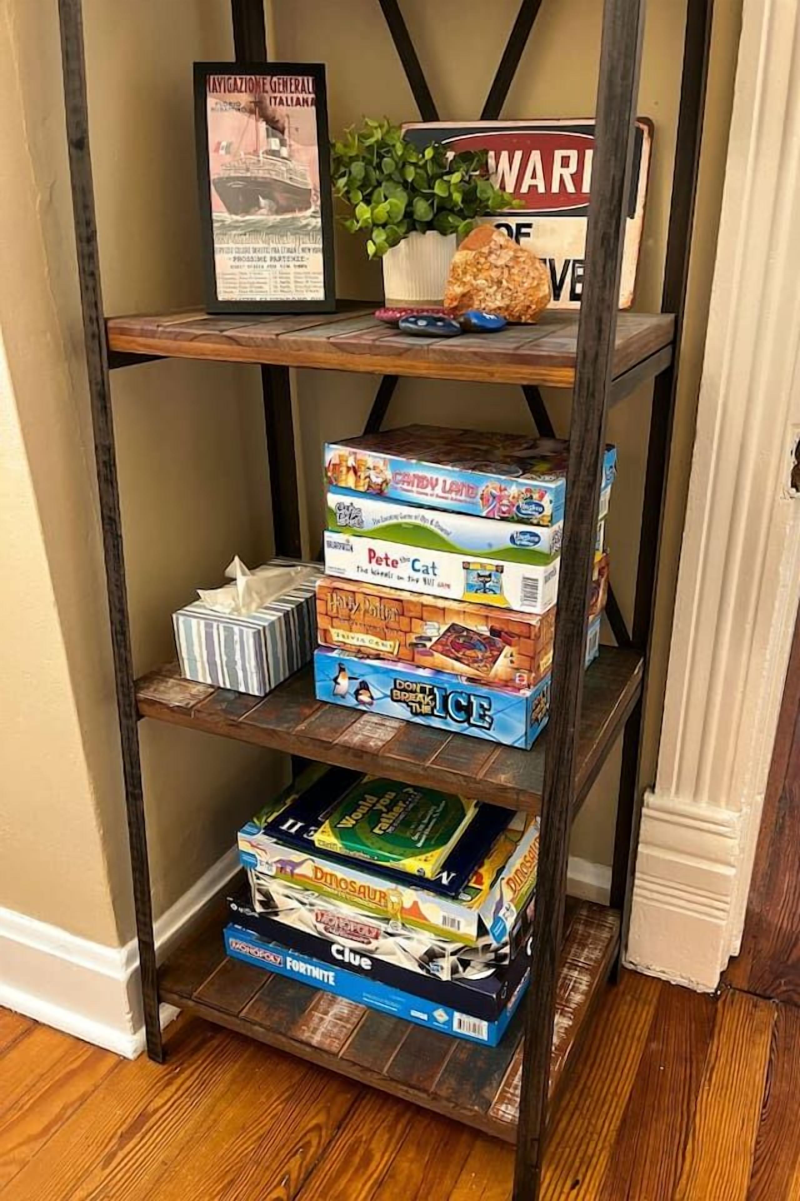 Une étagère en bois avec divers jeux de société et un tableau encadré.