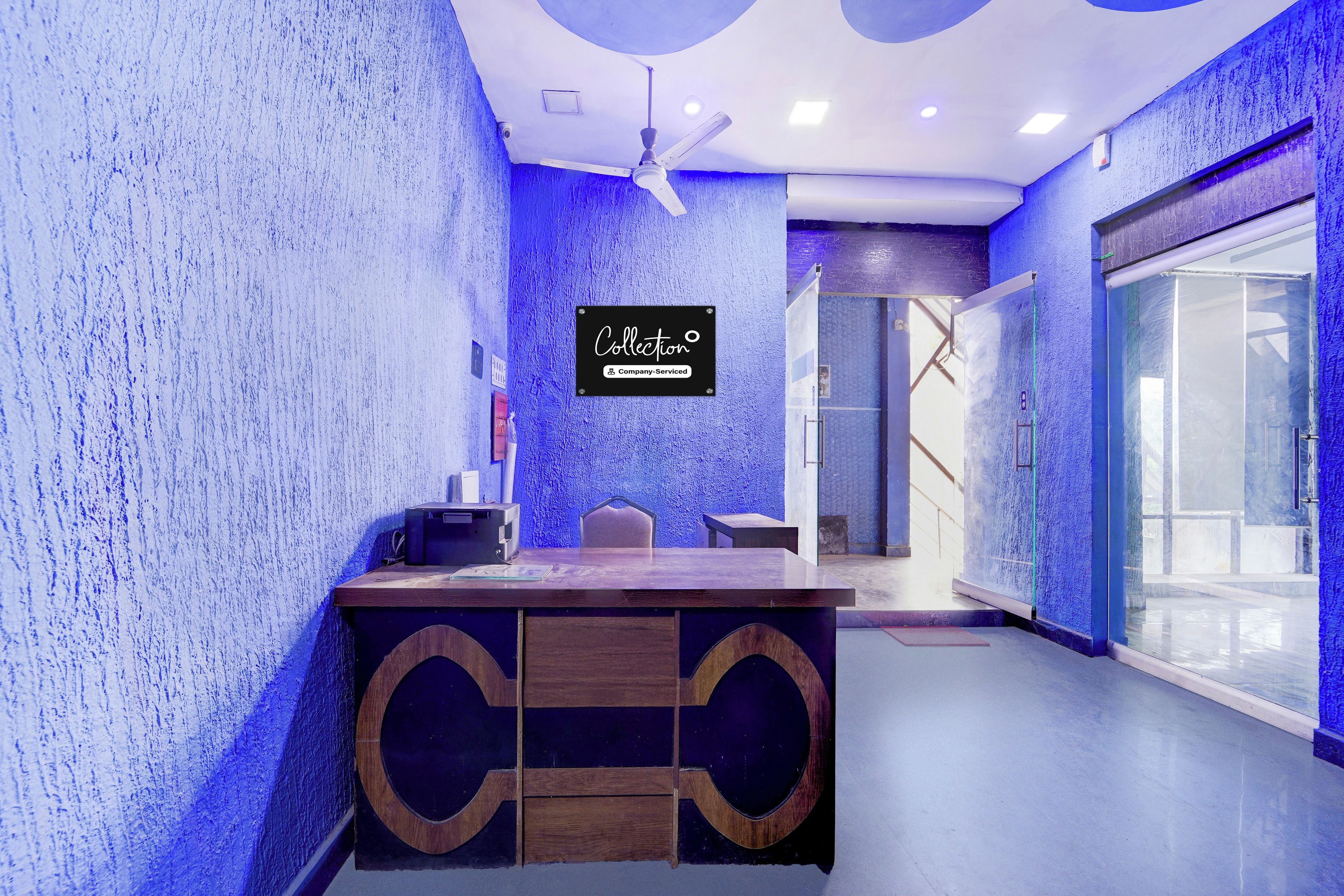 A reception area with a reception desk, a ceiling fan, and a sign indicating it's a company-serviced collection point.