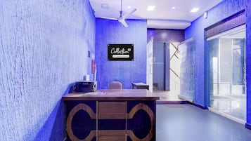 A reception area with a reception desk, a ceiling fan, and a sign indicating it's a company-serviced collection point.