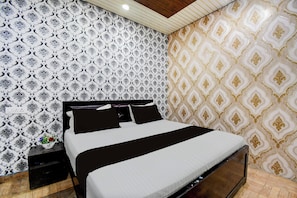 A bedroom with a bed, nightstands, and a wall with patterned wallpaper. - OYO Ambedkar Gorakhpur Residency (Lucknow)