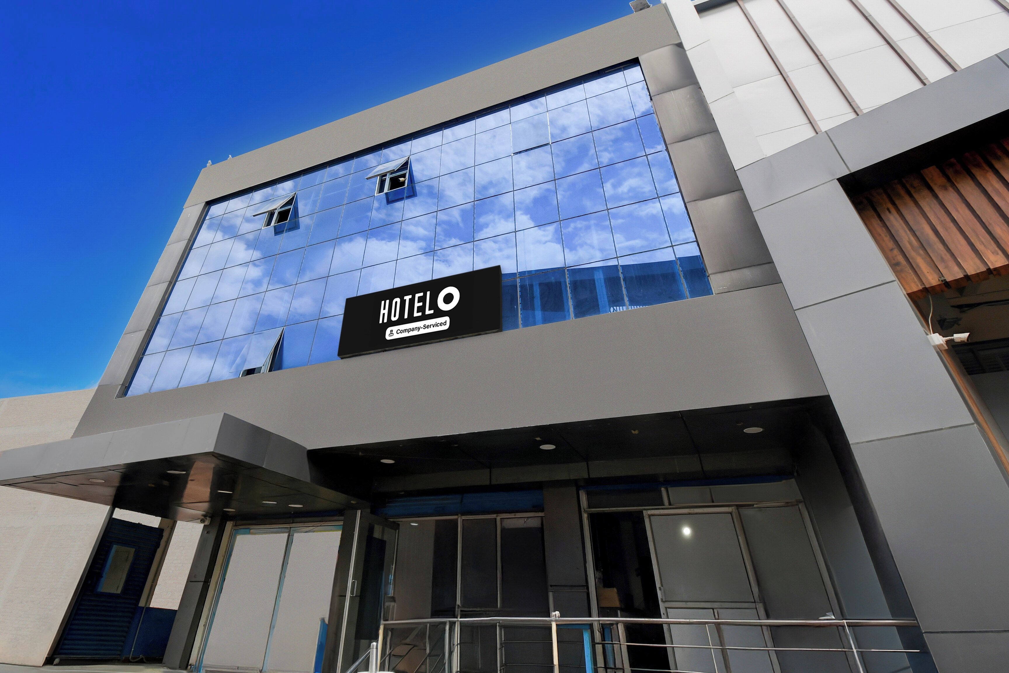 A modern hotel building with a glass facade reflecting the sky.