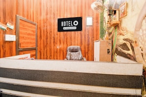 A hotel reception desk with a sign indicating it is a company-serviced hotel. - OYO Ambedkar Gorakhpur Residency (Lucknow)