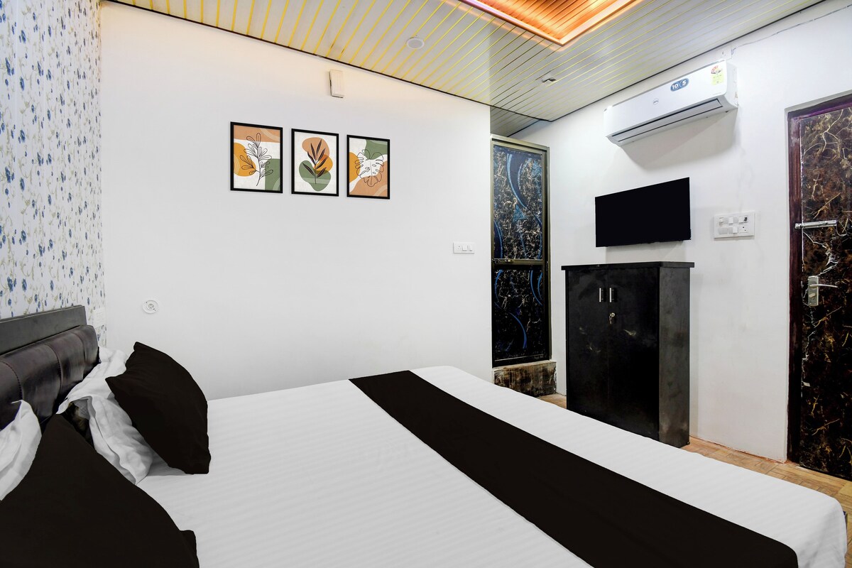 A hotel room with a bed, a flat-screen TV mounted on the wall, and a wardrobe.