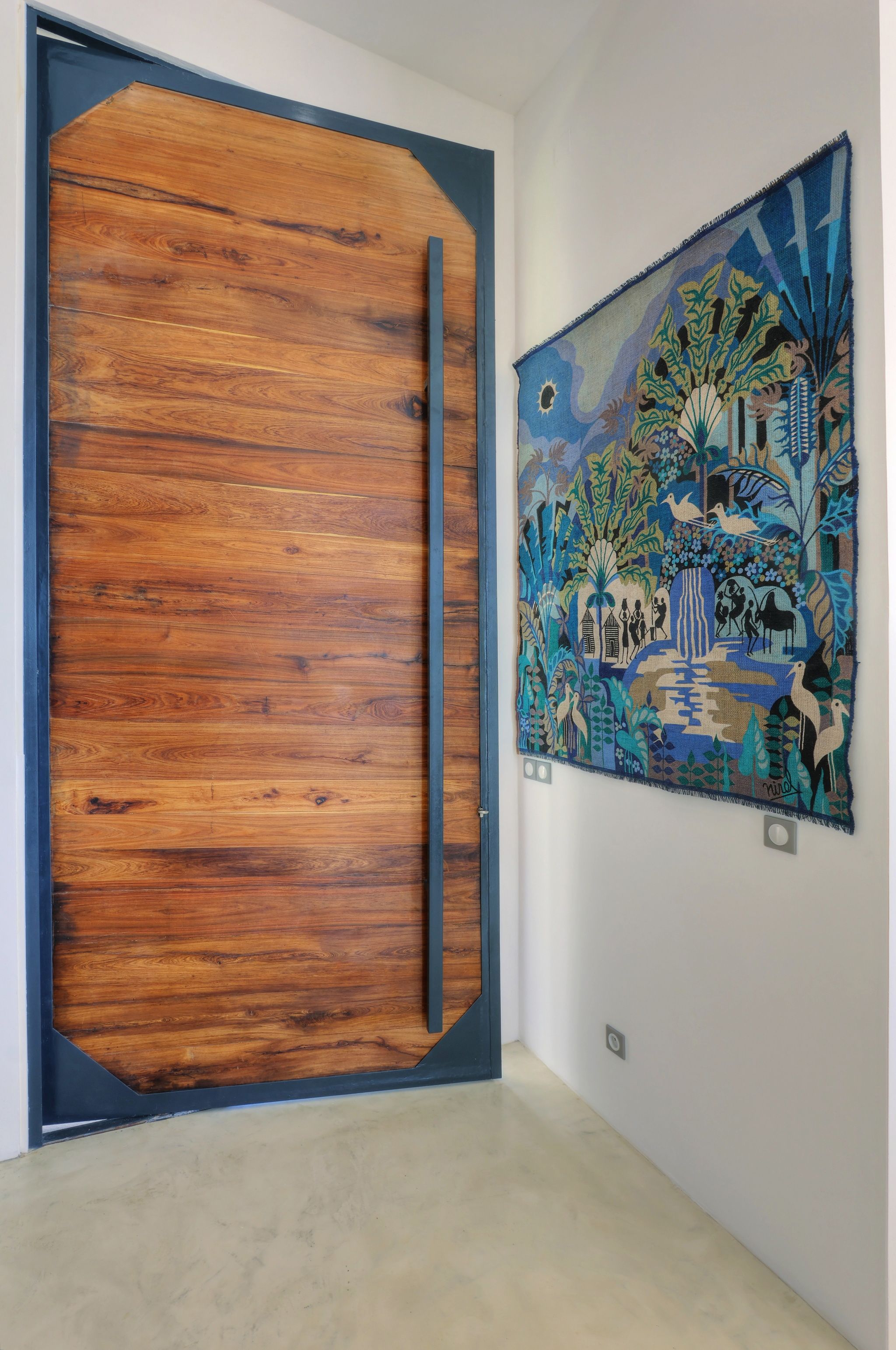 Una habitación con puerta de madera y un tapiz en la pared.