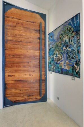 A room with a wooden door and a tapestry on the wall. - Stunning hill-top fully-equipped pool villa with sea view (Nosy Be)