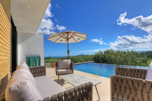 A modern outdoor seating area with a pool, a wooden wall, and a view of the landscape. - Stunning hill-top fully-equipped pool villa with sea view (Nosy Be)