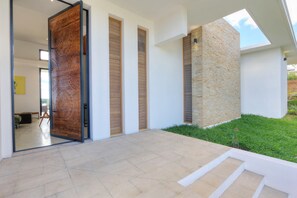 Ein modernes Haus mit einer großen Holztür, einer Steinmauer und einem gepflegten Rasen.