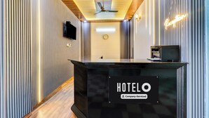 A hotel reception desk with a clock, a television, and a neon sign. - Super Hotel Junction Formerly Bhagwan (Dehradun)
