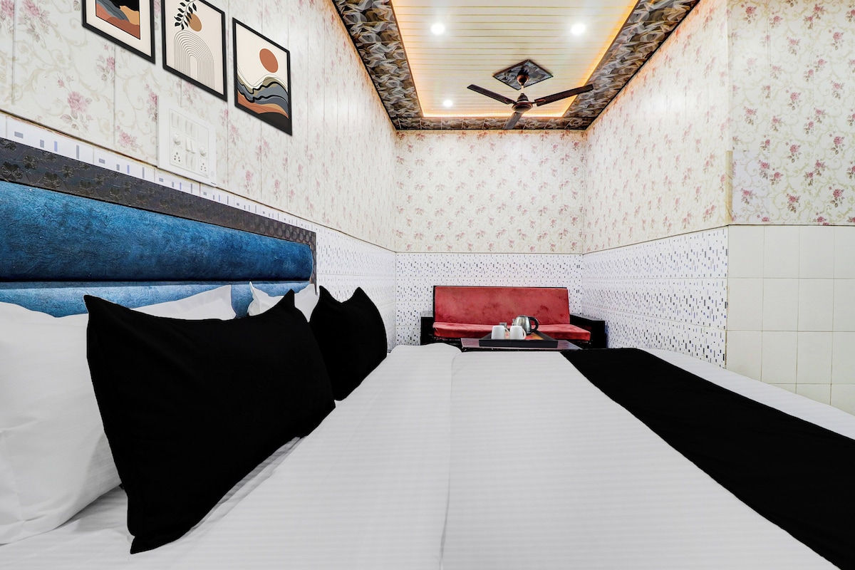 A hotel room with a bed, a red bench, and a ceiling fan.