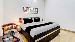 A hotel room with a bed, bedside table, lamp, and a small table with cups and a kettle. - Super Hotel Junction Formerly Bhagwan (Dehradun)