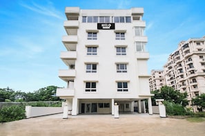 A multi-story hotel building with a sign indicating it is company serviced. - Hotel O Vizag IT Hill Rushikonda (Visakhapatnam)