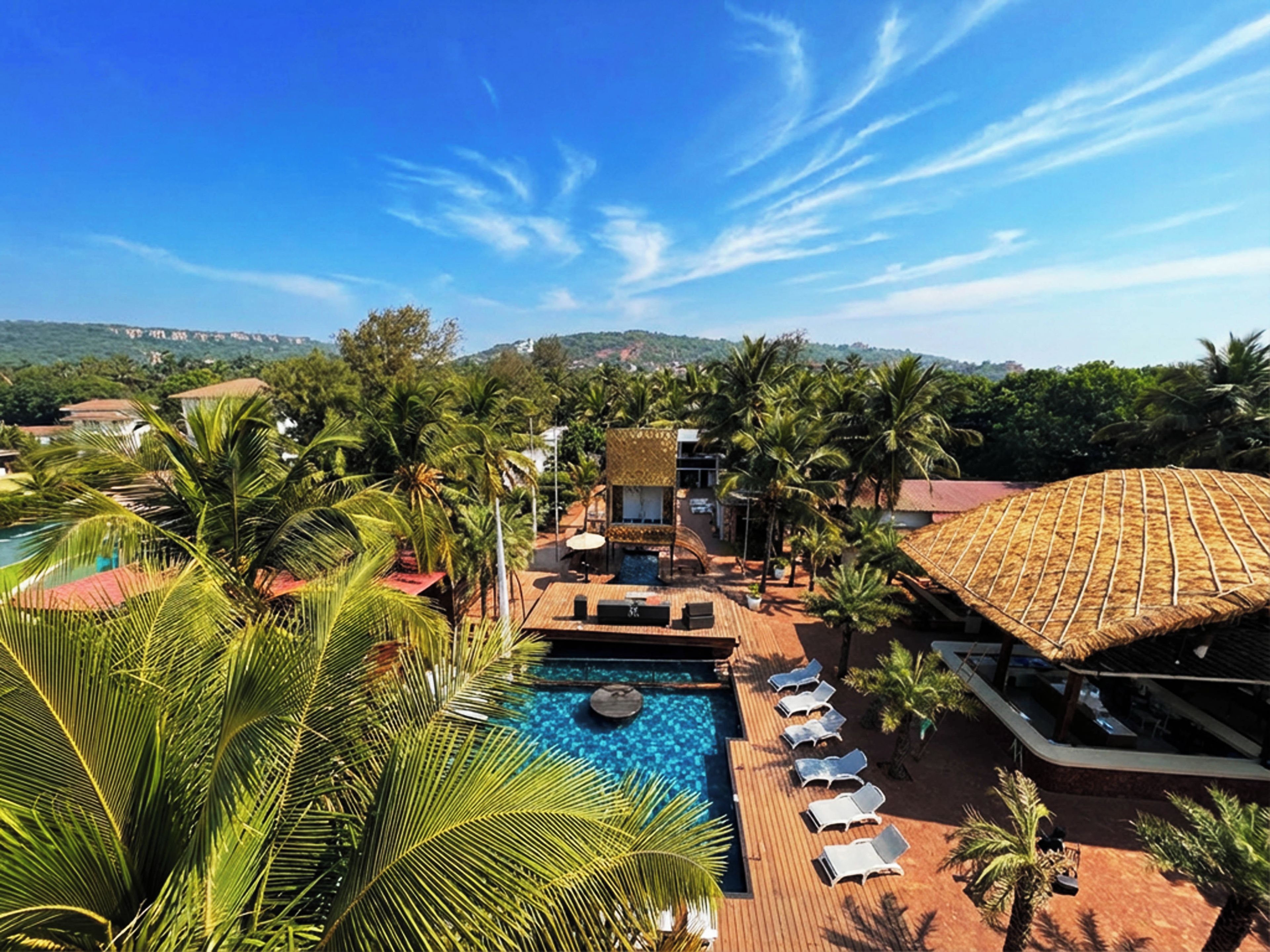 A resort with a swimming pool, lounge chairs, and palm trees.