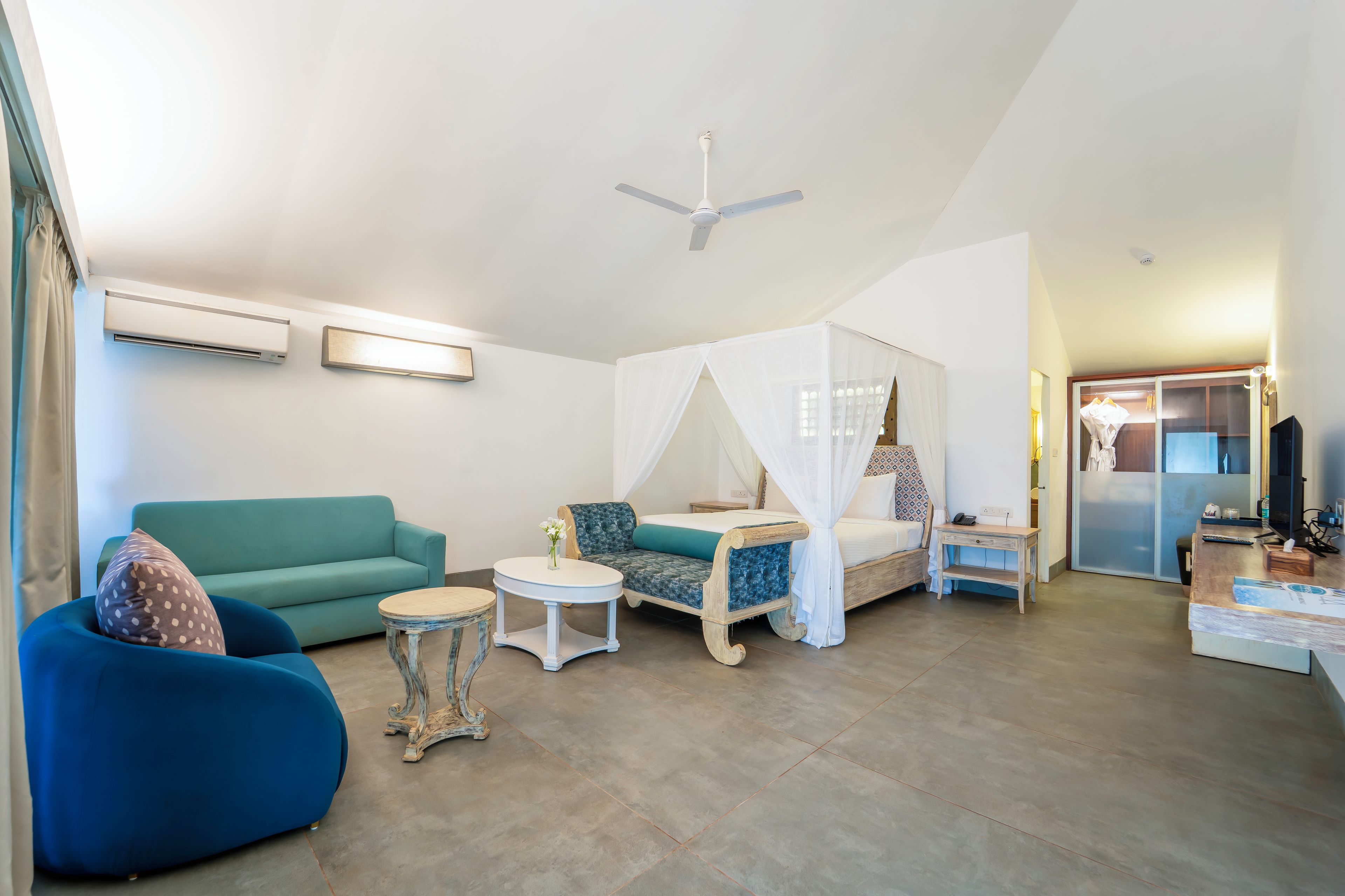 Un salon moderne comprenant un canapé, une table basse, une banquette-lit avec un baldaquin et un ventilateur de plafond.