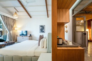 Ett modernt hotellrum med en stor säng, en tv och en matplats med bord och stolar.