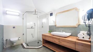 Un baño moderno con ducha envuelta en vidrio, tocador de madera y un espejo grande.