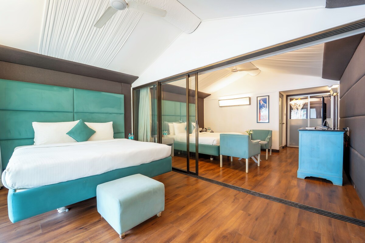 Ett modernt hotellrum med en stor säng, en sittgrupp och utsikt genom en glasdörr.
