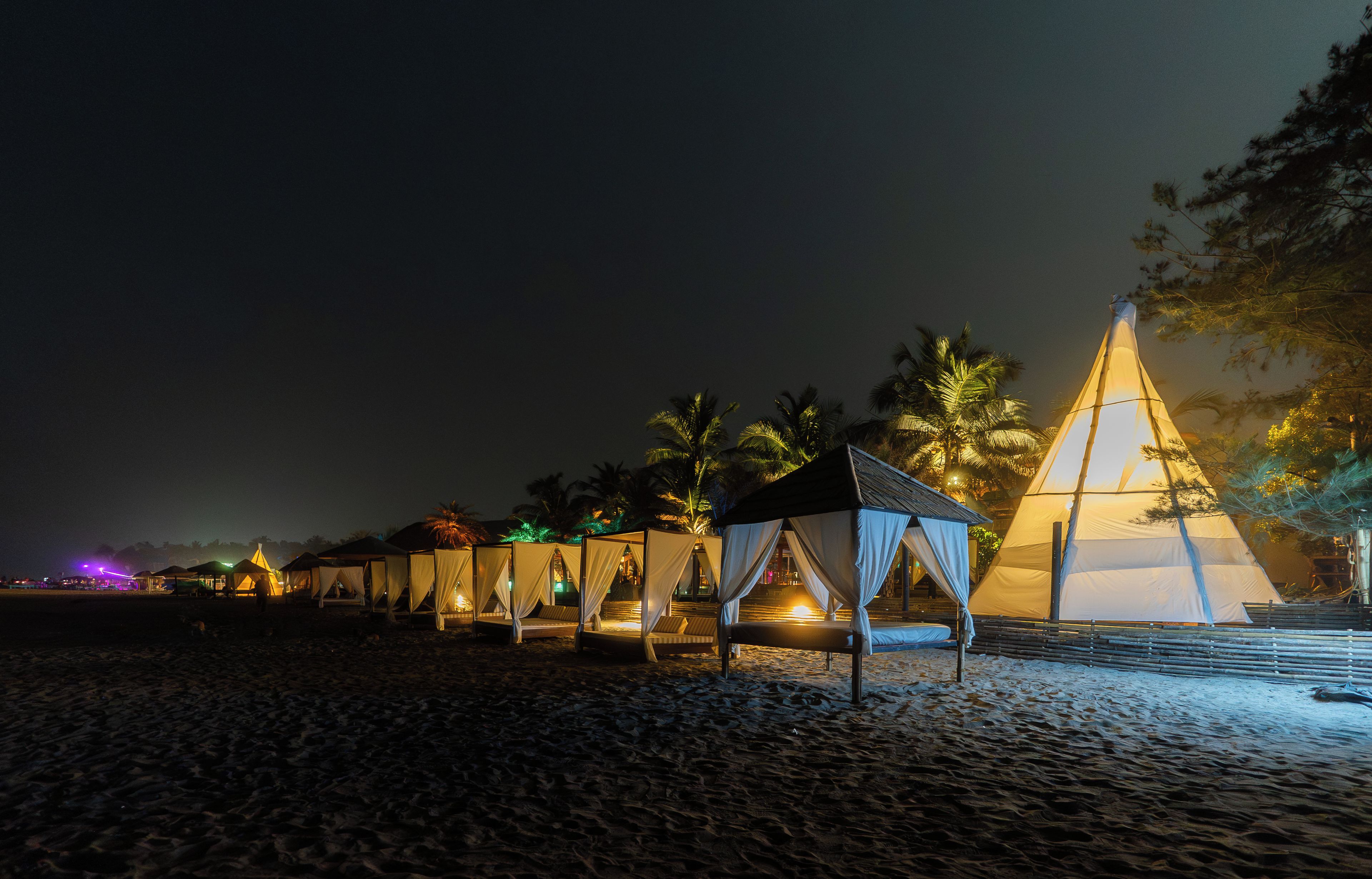 Ein Strand mit Zelten und einer großen pyramidenförmigen Struktur.