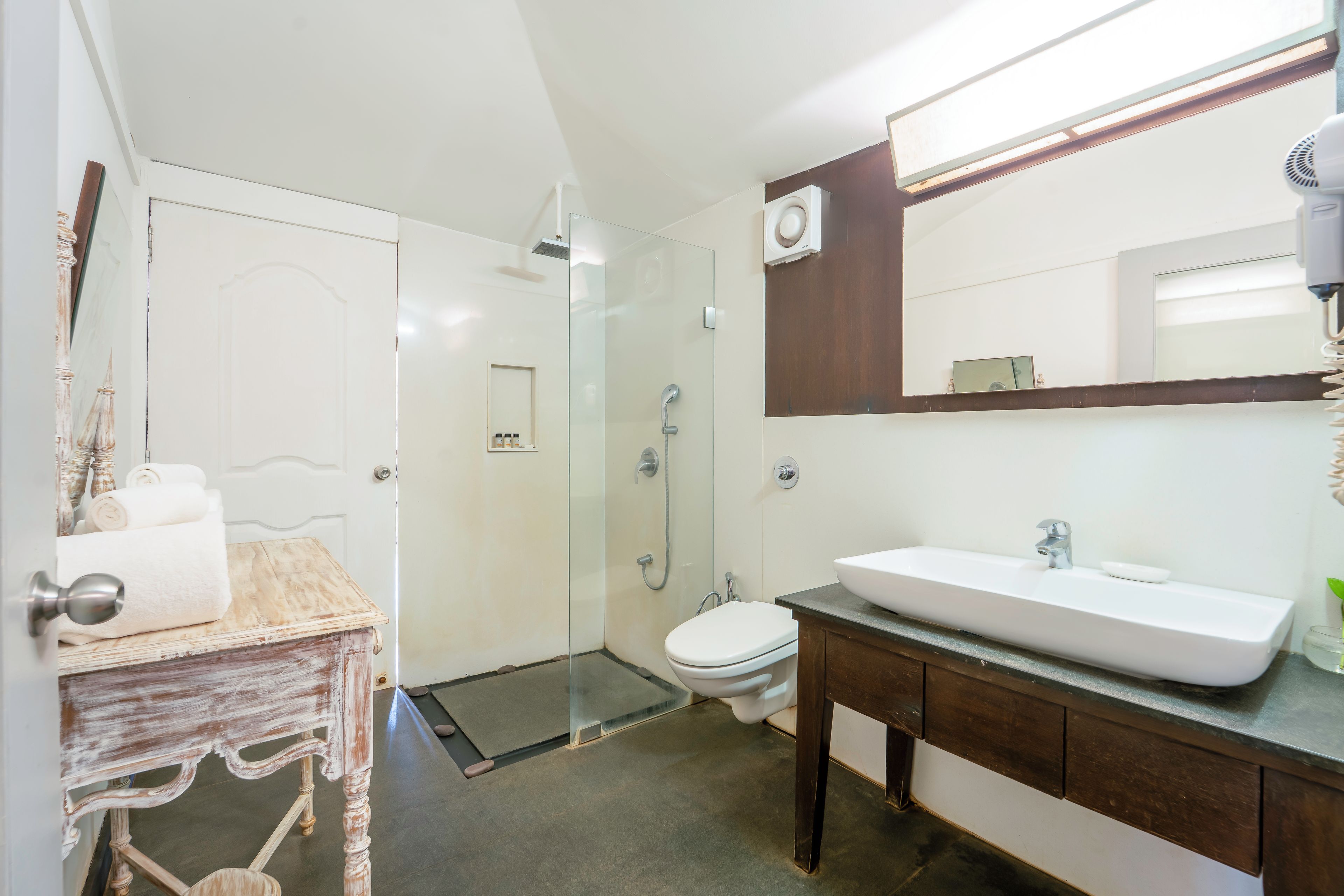 A modern bathroom with a glass shower enclosure, a white sink, and a wooden vanity.