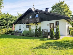 Une maison à deux étages avec un balcon, une antenne parabolique et une pelouse bien entretenue.
