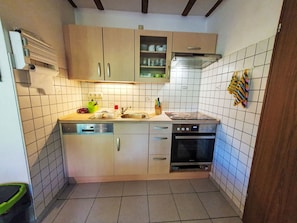 A compact kitchen with a dishwasher, oven, and a small countertop. - Ferienhaus Bussard by Interhome (Frielendorf)