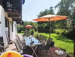 An outdoor patio with a table and chairs, surrounded by greenery. - Ferienhaus Bussard by Interhome (Frielendorf)