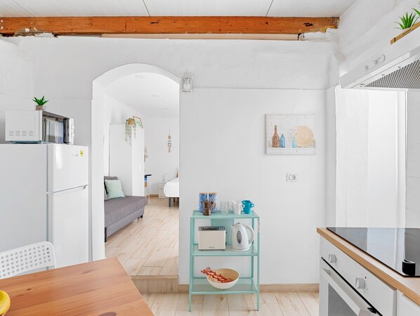 Eine moderne Küche mit Holzboden, weißen Wänden und einer zentralen Kochinsel mit diversen Küchenutensilien.