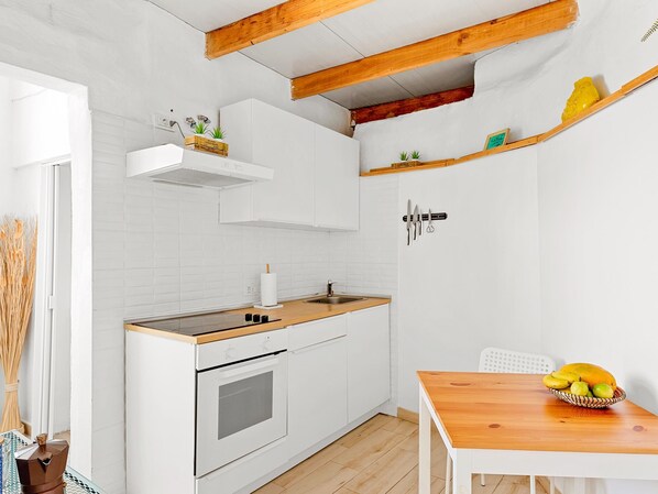 Eine kompakte Küche mit weißen Schränken, einer Holz Arbeitsplatte und einem eingebauten Backofen.