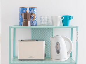 Ein Küchenbereich mit einem Toaster, einem Wasserkocher und einer Kaffeemaschine auf einem türkisfarbenen Regal.
