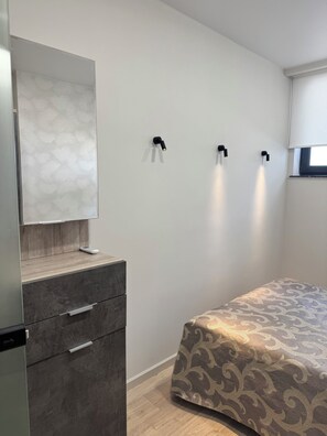 Quarto com cama, penteadeira, espelho e luminárias na parede.