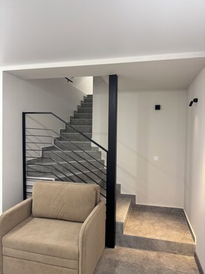A modern interior with a staircase, a beige armchair, and a minimalist design. - Modern 1-bedroom apartment in cool Yerevan with AC (Yerevan)