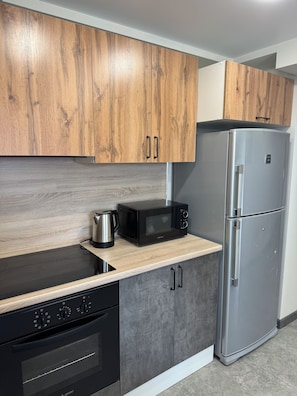 A modern kitchen with wooden cabinets, a stainless steel refrigerator, a microwave, and a stove. - Modern 1-bedroom apartment in cool Yerevan with AC (Yerevan)
