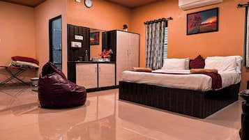 A bedroom with a bed, a wardrobe, a desk, and a bean bag chair.