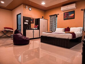 A bedroom with a bed, a wardrobe, a desk, and a bean bag chair.