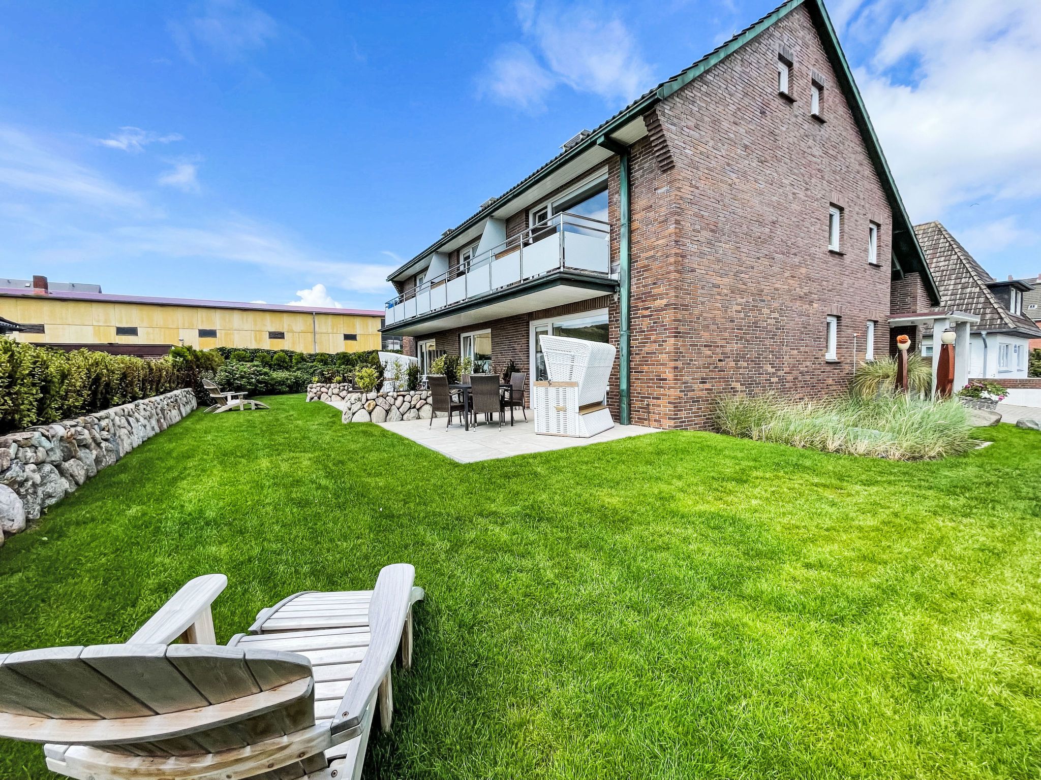 A two-story house with a brick exterior, a balcony, and a well-maintained lawn.