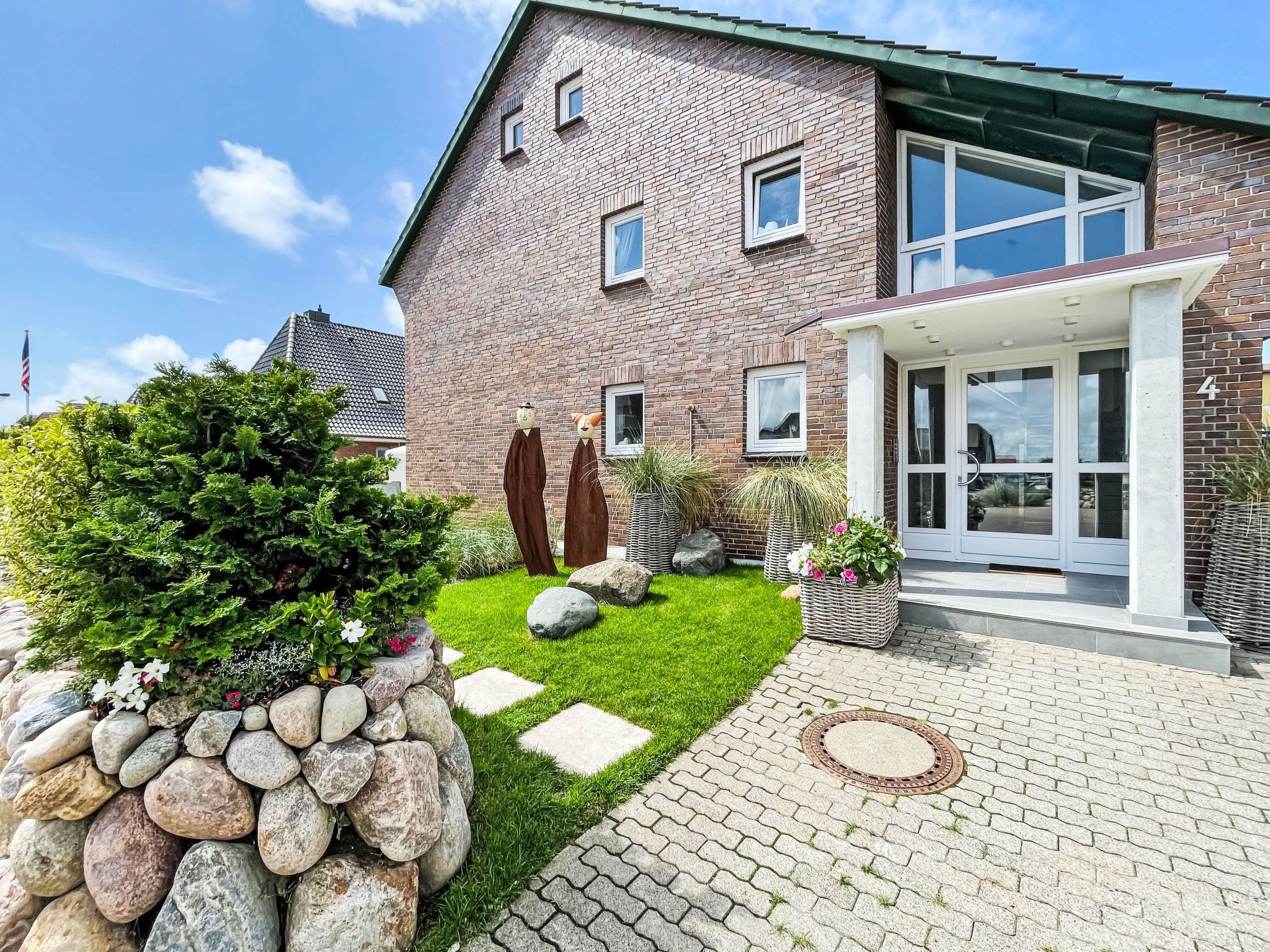 A two-story brick house with a front porch, a stone pathway, and a well-maintained lawn.