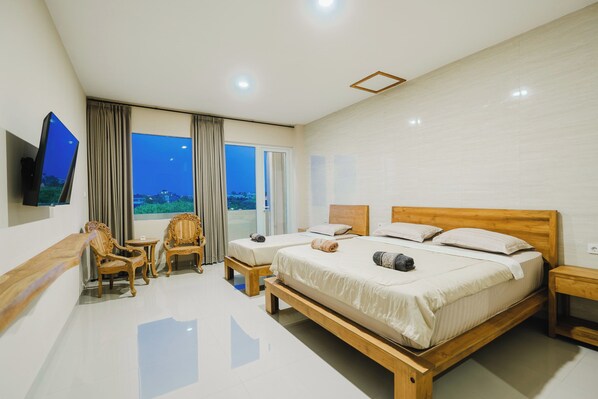 Quarto de hotel com duas camas, televisão, cadeira e vista para o exterior.