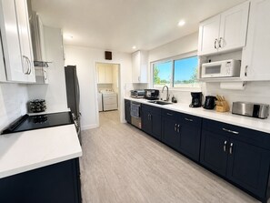 A modern kitchen with white cabinets, a black countertop, and a window providing a view of the outdoors. - 8651-Peaceful 4-bedroom house with AC in charming Elk Grove (Elk Grove)