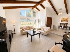 Ein geräumiges Wohnzimmer mit zwei Sofas, einem Couchtisch und einem Essbereich mit Stühlen und einem Tisch.