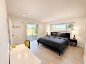 A bedroom with a bed, bedside lamps, a chair, and a view through a window. - 8651-Peaceful 4-bedroom house with AC in charming Elk Grove (Elk Grove)