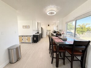 A modern kitchen with white cabinets, a stainless steel refrigerator, and a dining area with a table set for four. - 8651-Peaceful 4-bedroom house with AC in charming Elk Grove (Elk Grove)