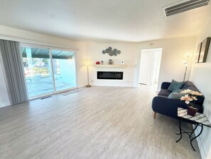 Ein geräumiges Wohnzimmer mit Kamin, einer Couch und einem Esstisch.