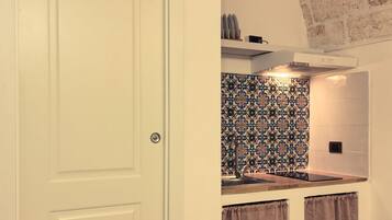 Una cucina con una porta bianca, zoccolo paraschizzi decorato e parete in mattoni.